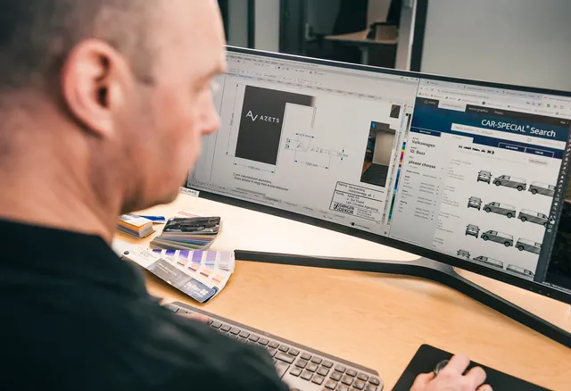 Person som sitter foran to pc-skjermer med design av bildekor